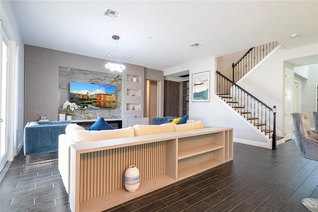 living area featuring wood tiled floor, visible vents, and stairs