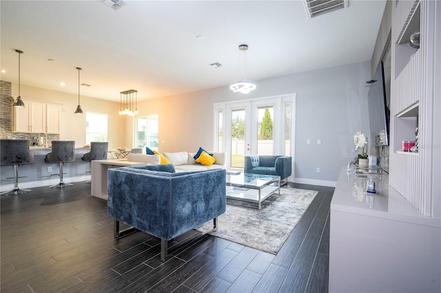 living room featuring a wealth of natural light, french doors, and dark wood-style flooring