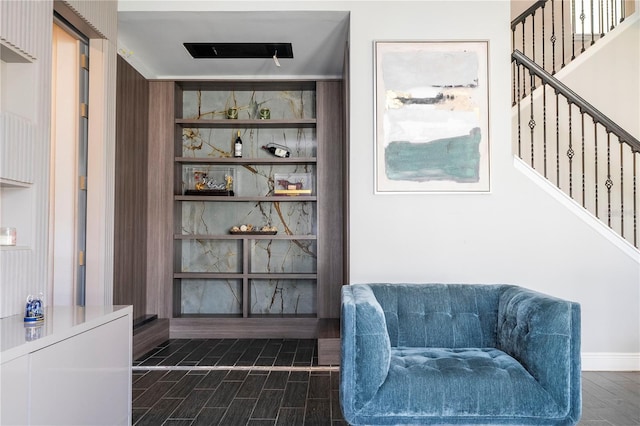 living area featuring built in features, dark wood-type flooring, stairway, and baseboards