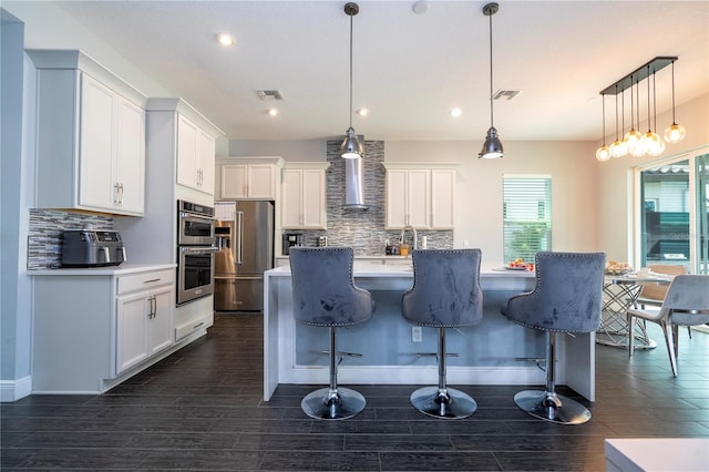 kitchen with appliances with stainless steel finishes, visible vents, wall chimney range hood, and decorative backsplash