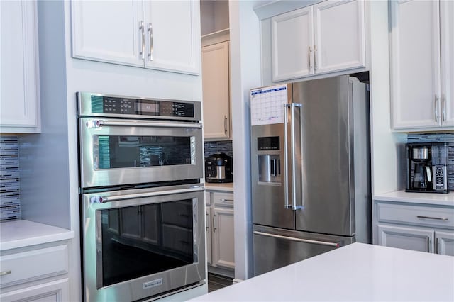 kitchen featuring white cabinetry, stainless steel appliances, decorative backsplash, and light countertops