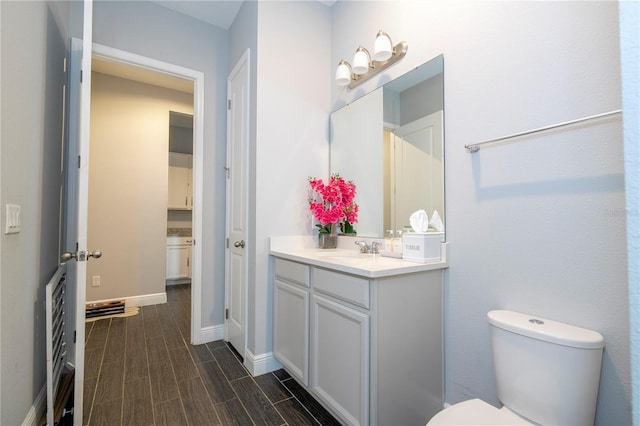 bathroom with toilet, wood tiled floor, baseboards, and vanity