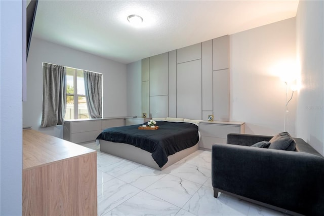 bedroom featuring marble finish floor and a textured ceiling