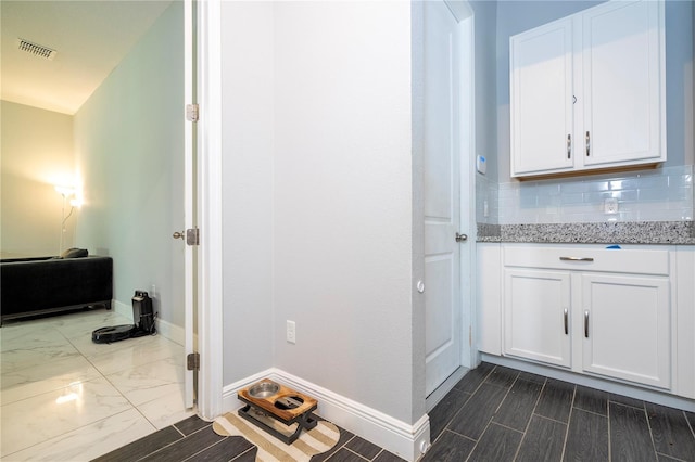 bathroom with marble finish floor, baseboards, and decorative backsplash