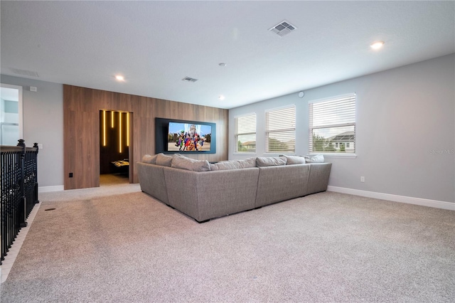 living room featuring visible vents, wood walls, light carpet, and baseboards