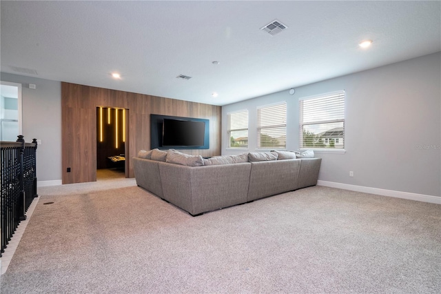 living area featuring visible vents, wood walls, light carpet, and baseboards