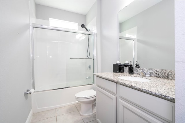 bathroom with bath / shower combo with glass door, vanity, tile patterned flooring, and toilet