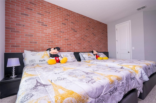 bedroom featuring carpet flooring, visible vents, a textured ceiling, and brick wall