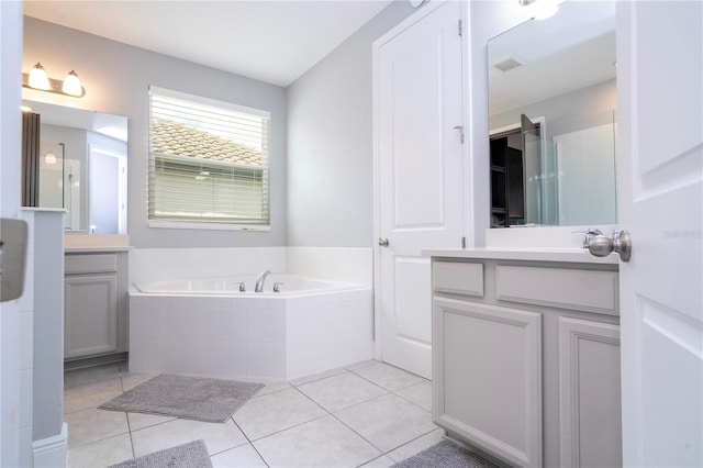 bathroom with a garden tub, visible vents, two vanities, and tile patterned floors