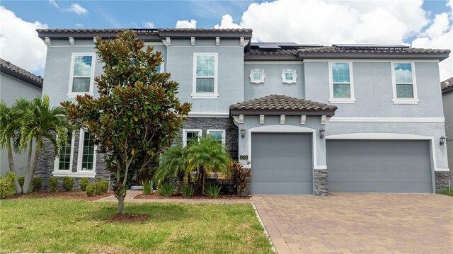 8324 Ludington Cir, Orlando, FL 32836 - view of front of home with an attached garage, decorative driveway, stucco siding, a tiled roof, and stone siding
