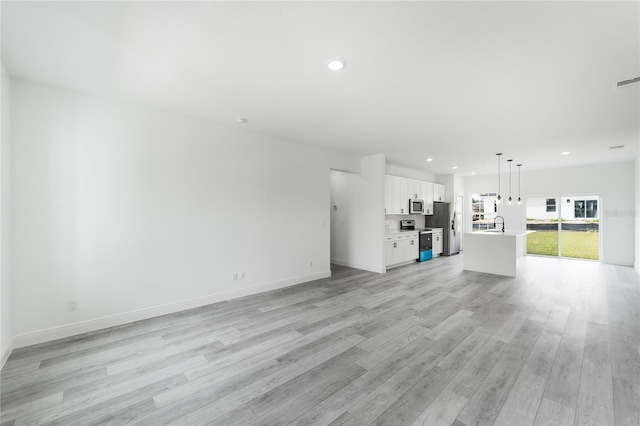 unfurnished living room with sink and light hardwood / wood-style flooring