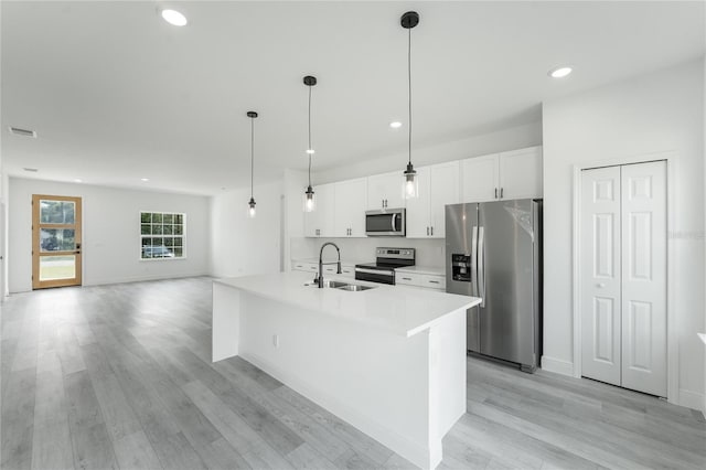 kitchen with white cabinets, light hardwood / wood-style flooring, appliances with stainless steel finishes, sink, and an island with sink