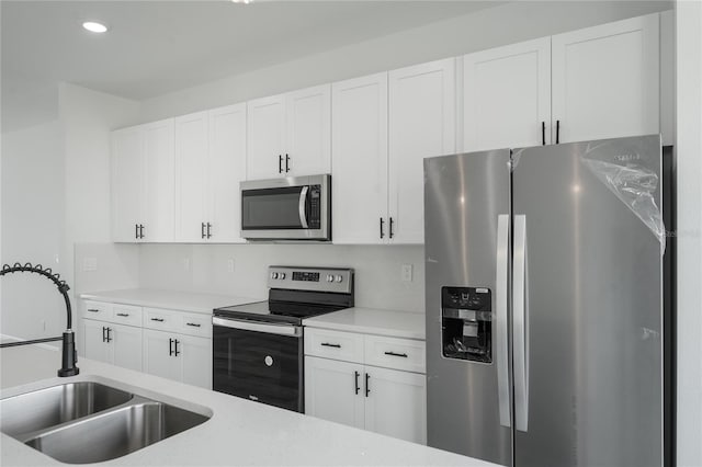 kitchen with appliances with stainless steel finishes, white cabinetry, and sink