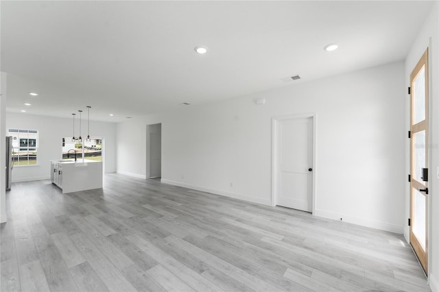 unfurnished living room with light hardwood / wood-style flooring and sink