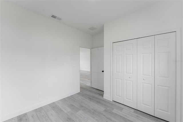 unfurnished bedroom with light wood-type flooring and a closet