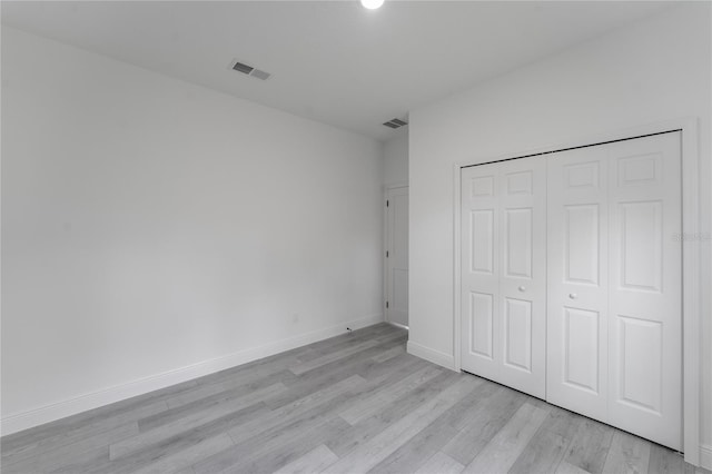 unfurnished bedroom with light hardwood / wood-style flooring and a closet