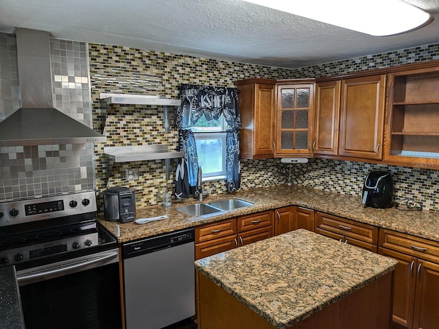 kitchen featuring appliances with stainless steel finishes, backsplash, wall chimney exhaust hood, sink, and a kitchen island