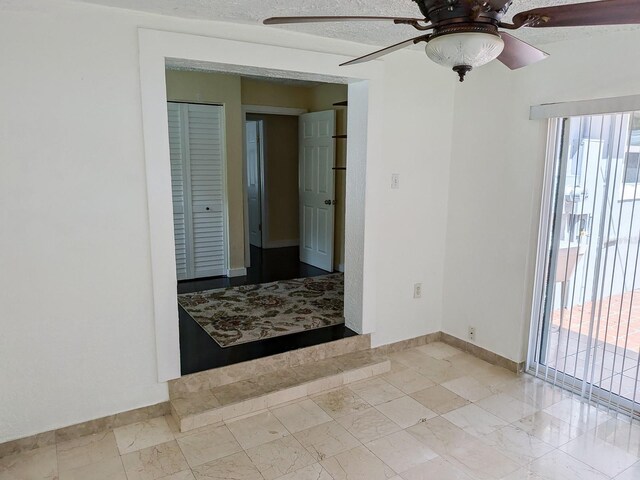 tiled empty room featuring ceiling fan