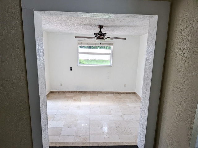 spare room featuring ceiling fan, light tile patterned flooring, and a textured ceiling