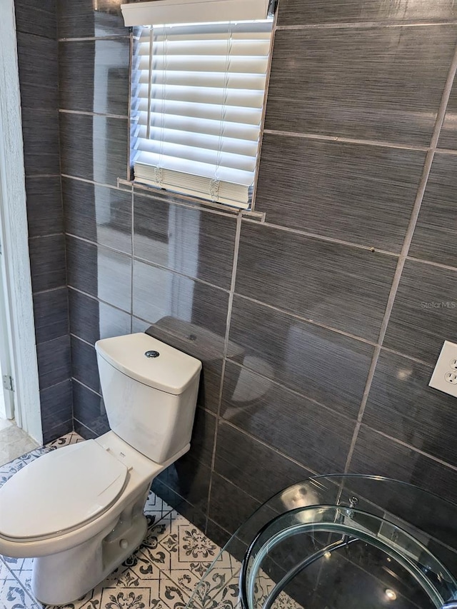 bathroom featuring tile walls, tile patterned floors, and toilet