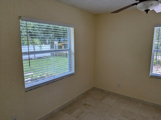 tiled spare room with ceiling fan and a textured ceiling