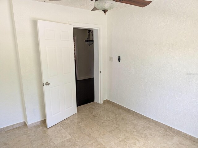 tiled spare room featuring ceiling fan