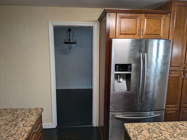 kitchen with stainless steel fridge with ice dispenser and stone counters