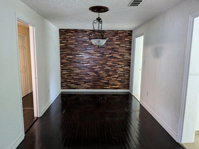 unfurnished dining area featuring a textured ceiling and hardwood / wood-style floors