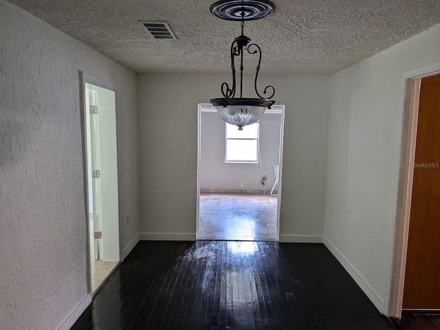 unfurnished dining area with a textured ceiling, hardwood / wood-style floors, and a chandelier