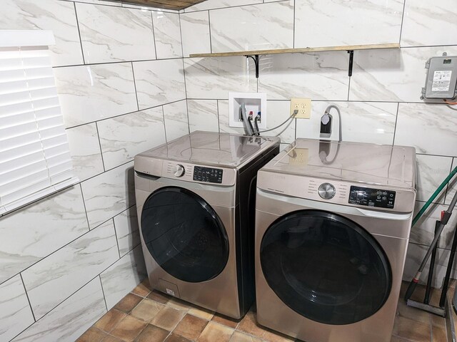 clothes washing area with tile walls, washer and dryer, and light tile patterned floors