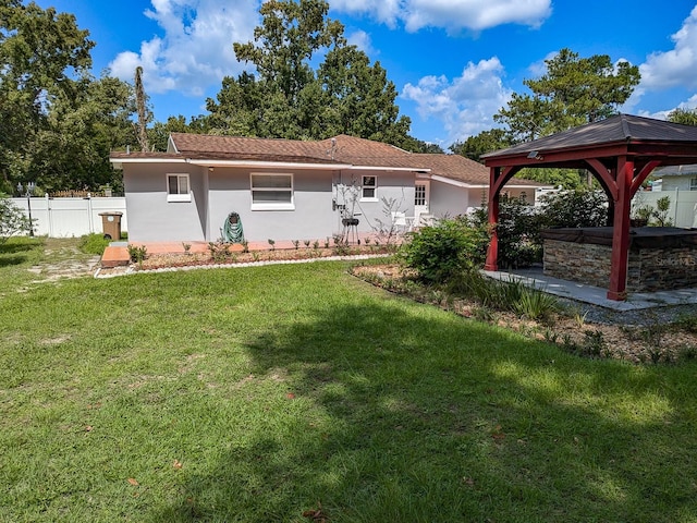 rear view of house featuring a gazebo and a yard