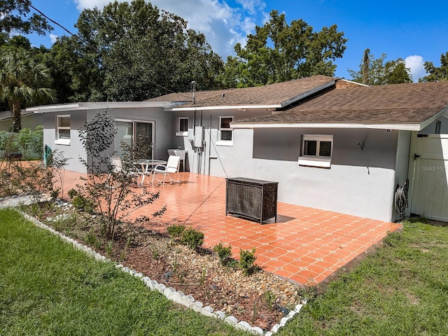 back of property featuring a patio area and a lawn