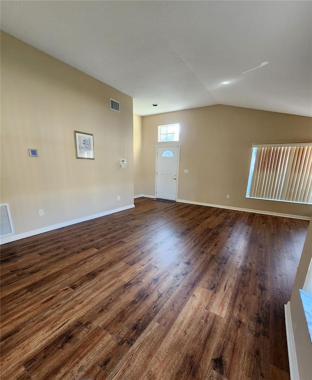 interior space featuring lofted ceiling, baseboards, visible vents, and dark wood-style flooring