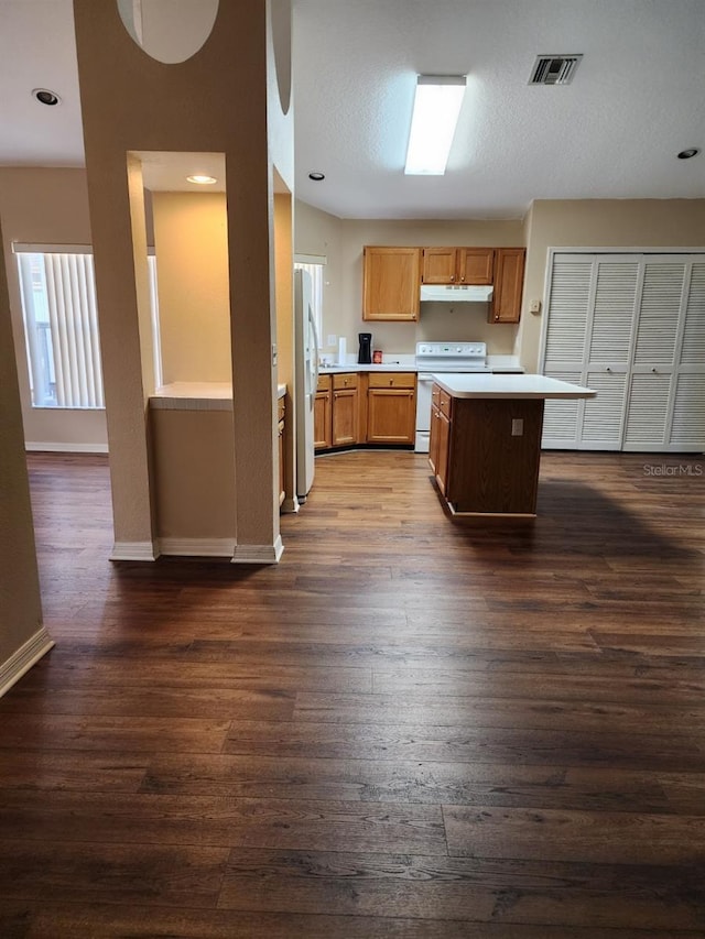 kitchen with dark wood finished floors, visible vents, light countertops, white appliances, and under cabinet range hood