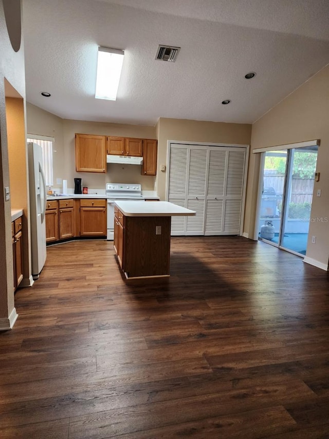 kitchen featuring light countertops, visible vents, dark wood-type flooring, white appliances, and under cabinet range hood