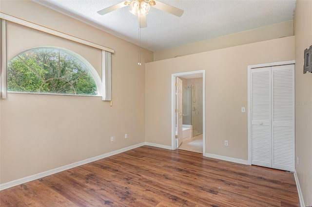 unfurnished bedroom with ensuite bath, a textured ceiling, ceiling fan, and dark hardwood / wood-style floors