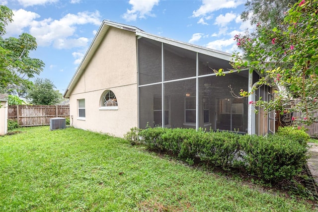 back of property with a lawn, stucco siding, a sunroom, and fence