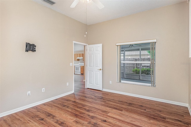 spare room with a textured ceiling, ceiling fan, hardwood / wood-style floors, and high vaulted ceiling