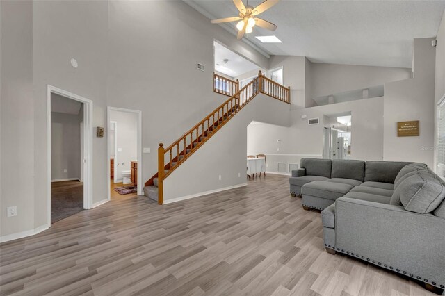 living room featuring ceiling fan, high vaulted ceiling, and light wood-type flooring