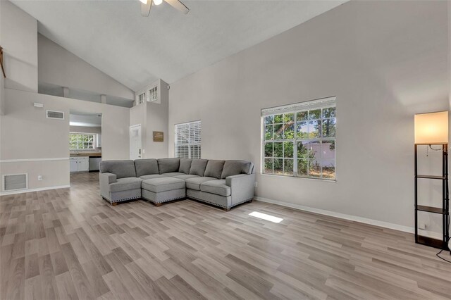 living room featuring light wood-type flooring, high vaulted ceiling, and a healthy amount of sunlight