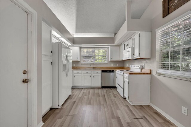 kitchen featuring light hardwood / wood-style flooring, butcher block countertops, white cabinets, sink, and white appliances