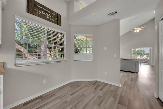 interior space with ceiling fan, high vaulted ceiling, a healthy amount of sunlight, and wood-type flooring