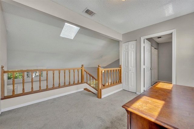 interior space with a textured ceiling, carpet, and lofted ceiling with skylight