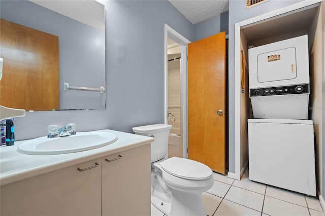 bathroom featuring tile patterned flooring, a textured ceiling, toilet, stacked washer / dryer, and vanity