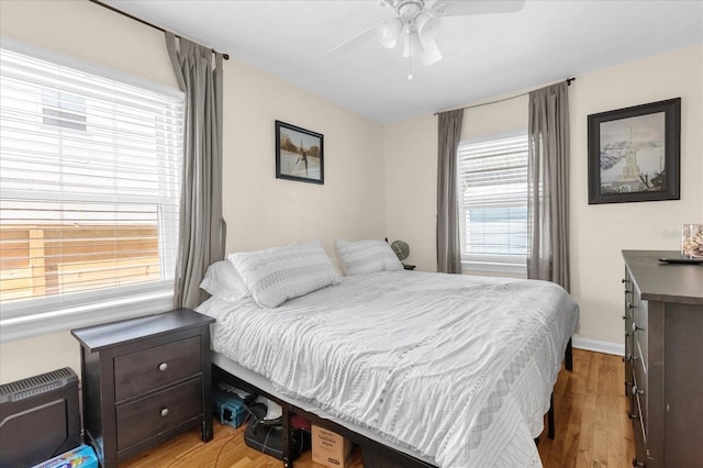 bedroom with ceiling fan, light hardwood / wood-style floors, and multiple windows