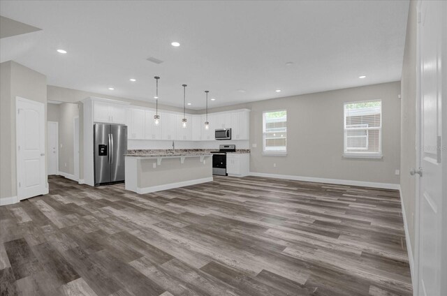 kitchen featuring a kitchen island, stainless steel appliances, decorative light fixtures, and wood-type flooring