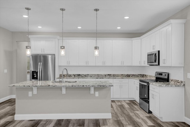 kitchen featuring a kitchen island with sink, stainless steel appliances, a sink, white cabinetry, and hanging light fixtures