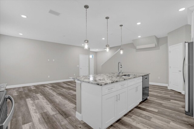 kitchen with light wood-type flooring, sink, a center island with sink, and white cabinetry