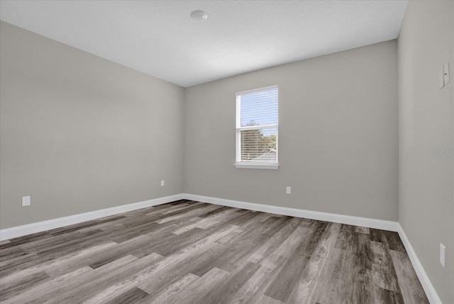 spare room featuring baseboards and light wood finished floors