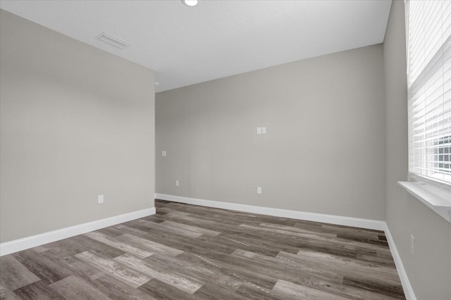 spare room featuring visible vents, baseboards, and wood finished floors